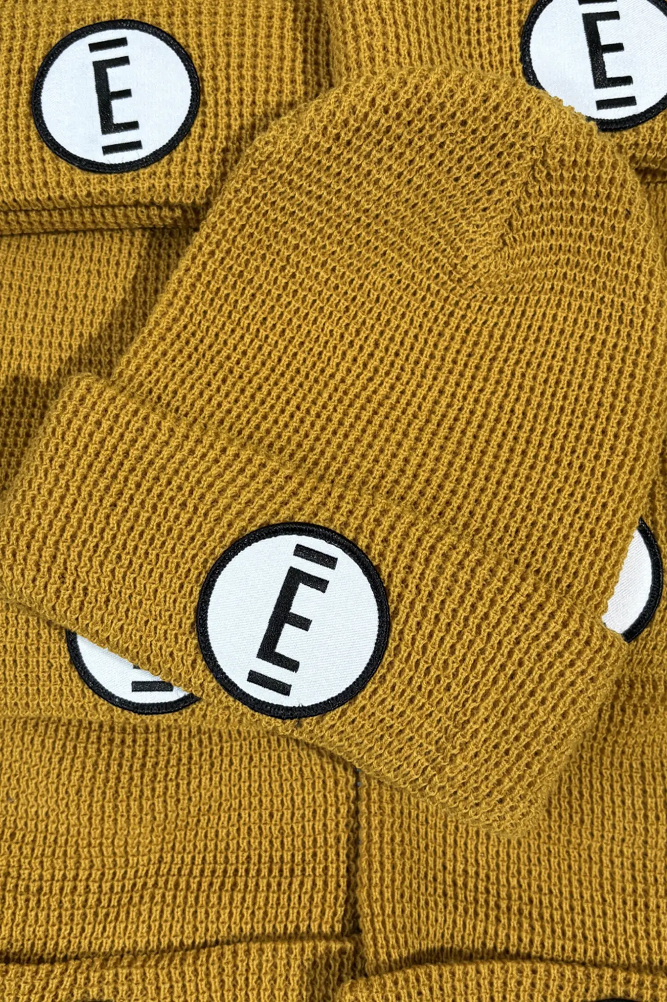 A gold beanie with black and white patch for The Exchange